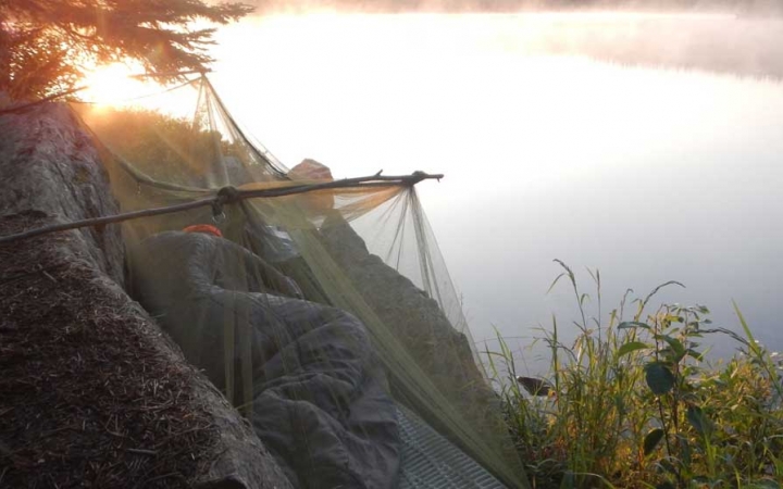 A person rests on a cliff high above a body of water. 